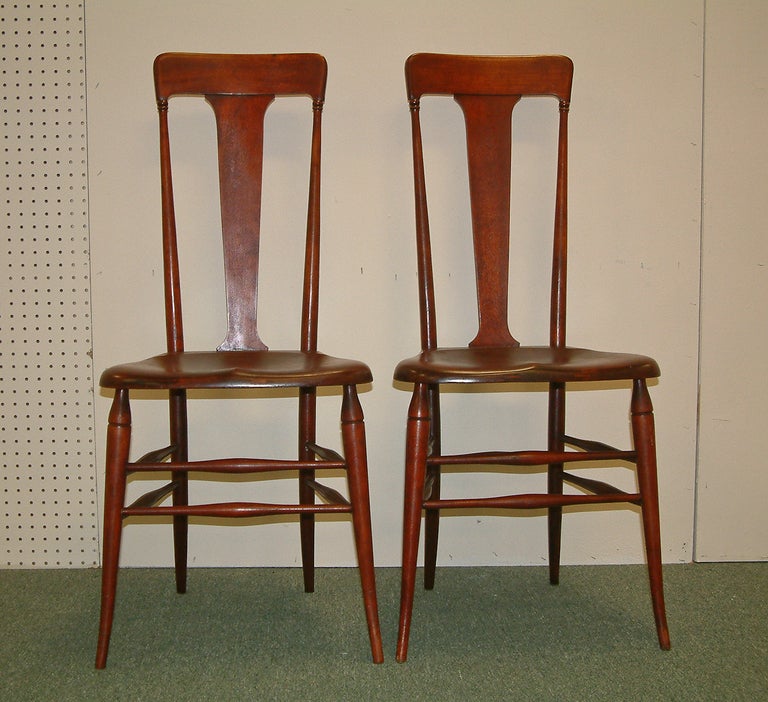 A stylized pair of highback cherrywood chairs inspired by The Arts and Crafts and The Art Nouveau Movements around the turn of the 20th century.  The chairs have a contoured seat with mortise and tenon construction and partial paper manufacture's